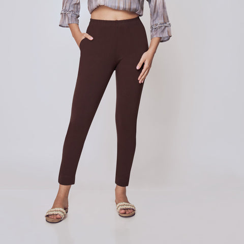 Woman wearing a patterned top and brown pants on a white background