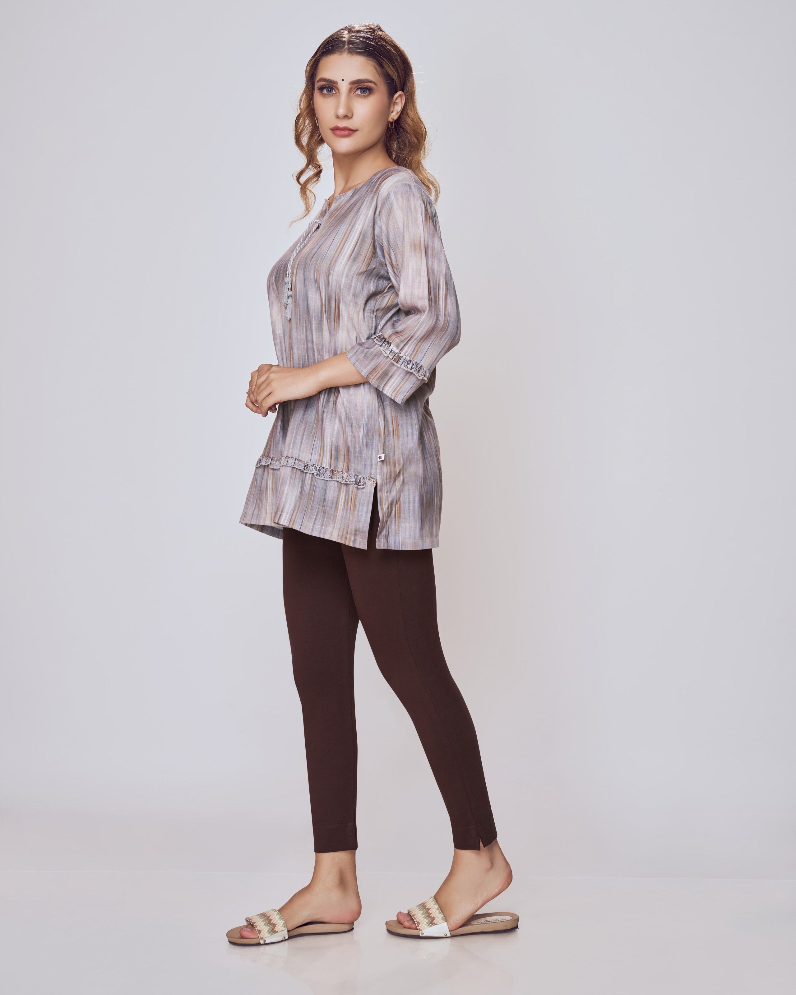 Woman wearing a plaid shirt and dark pants on a white background