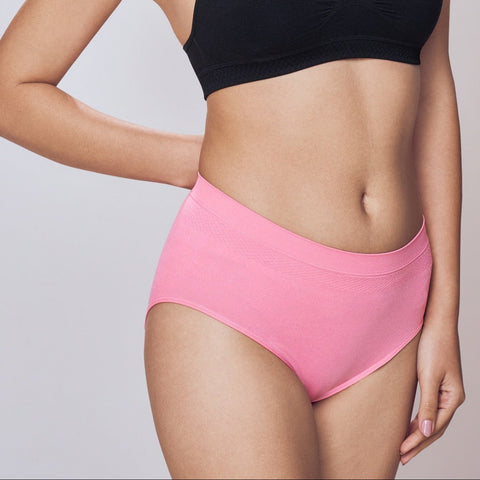 Woman wearing a black sports bra and pink Lady Care Air V Hipster Panty on a plain background