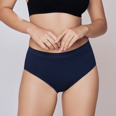 Woman wearing a black sports bra and navy Lady Care Air V Hipster Panty on a plain background