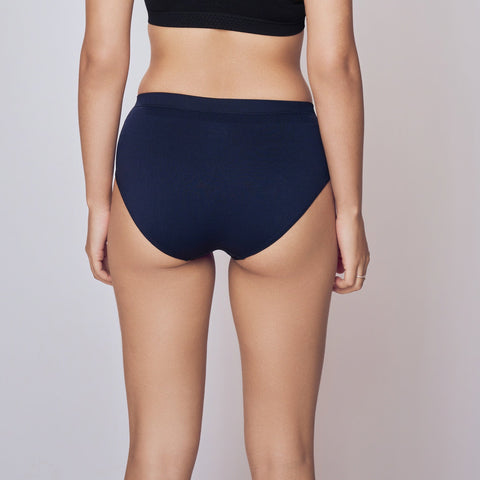 Woman wearing a black sports bra and navy Lady Care Air V Hipster Panty on a gray background