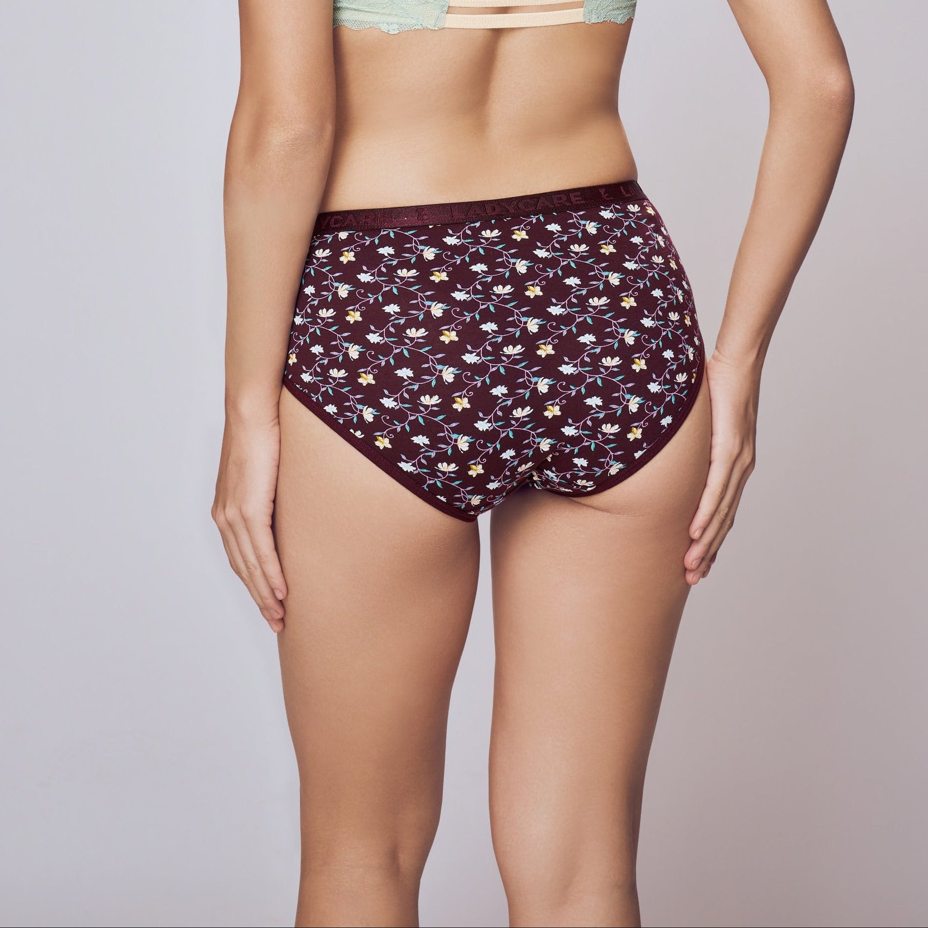 Woman wearing a strapless top and patterned underwear on a plain background