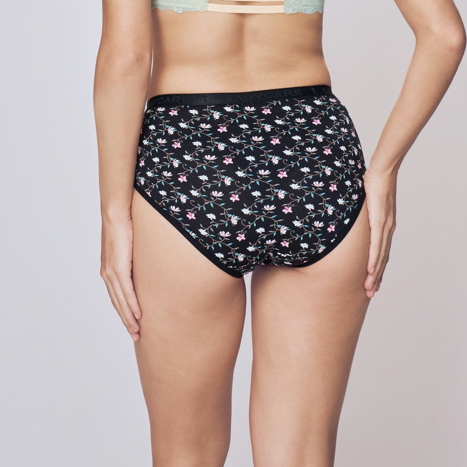 Woman wearing a strapless top and patterned high-waisted shorts on a plain background