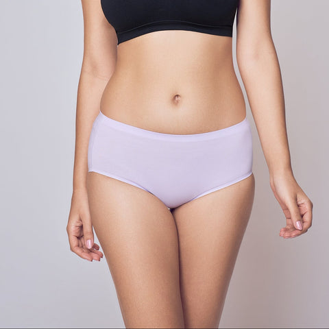 Woman wearing a black sports bra and light purple Lady Care Think Hipster Panty on a gray background