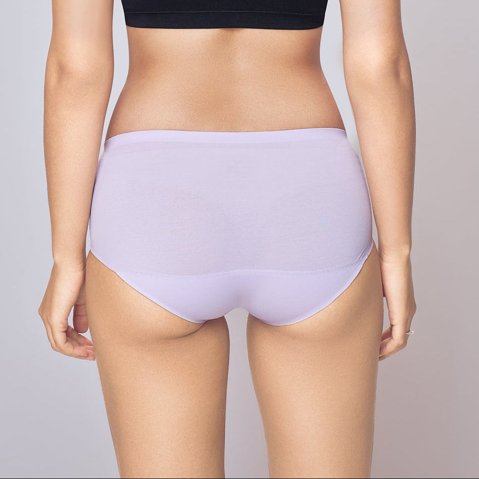 Woman wearing a black bra and light purple Lady Care think Panty on a gray background