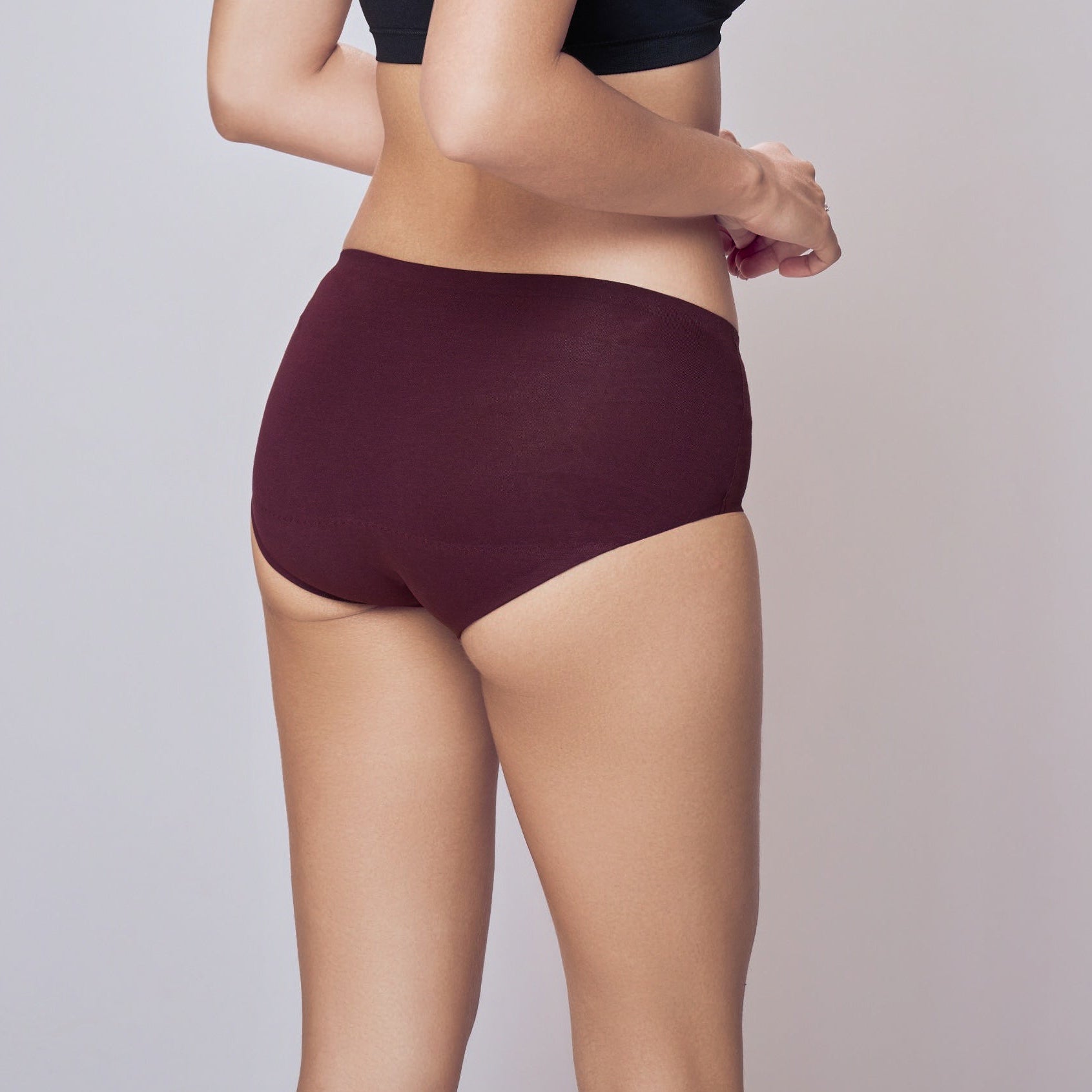 Woman wearing a black bra and maroon    Lady Care Think Hipster Panty  underwear on a gray background