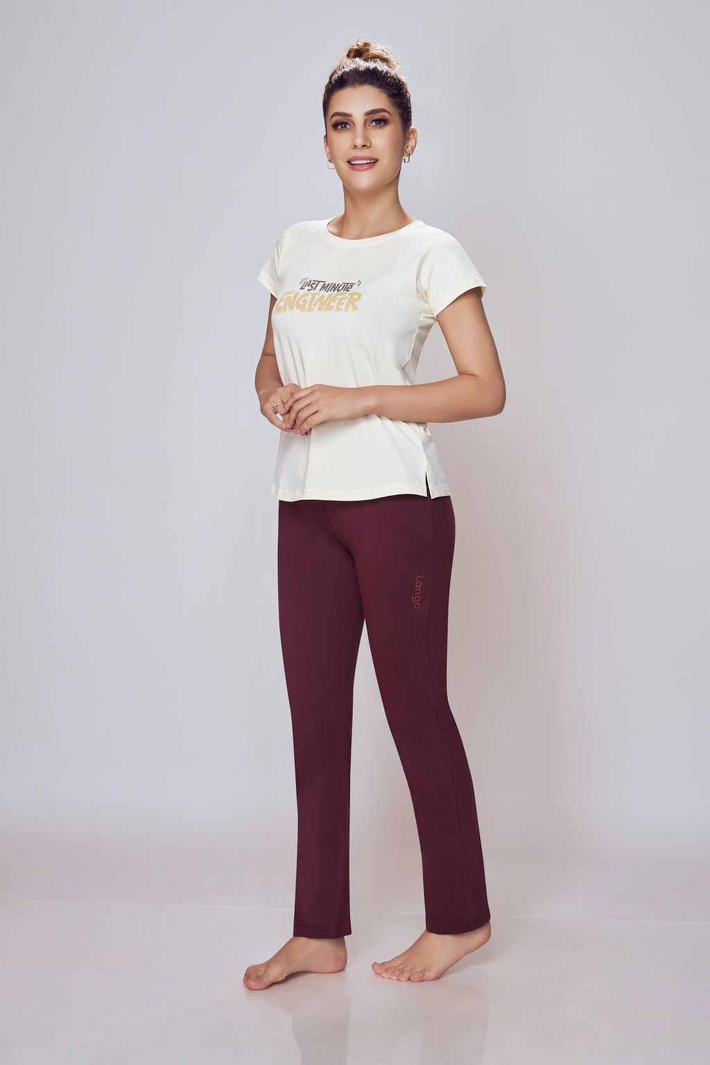 Woman wearing a white t-shirt with text and maroon leggings on a light gray background