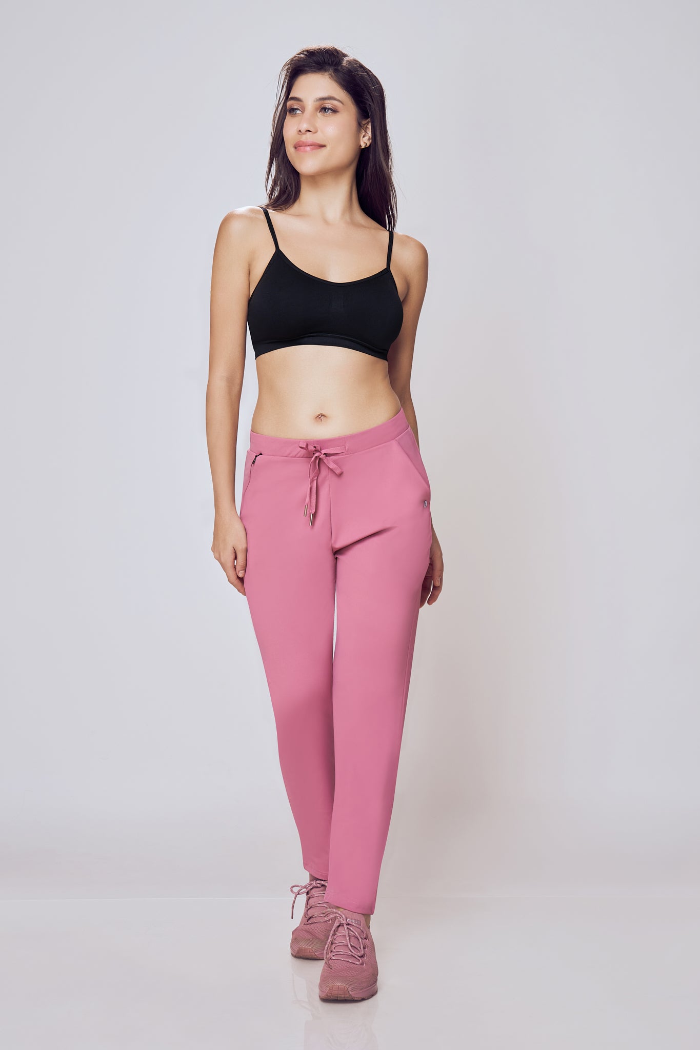 Woman wearing a black sports bra and Onion travel pant on a white background