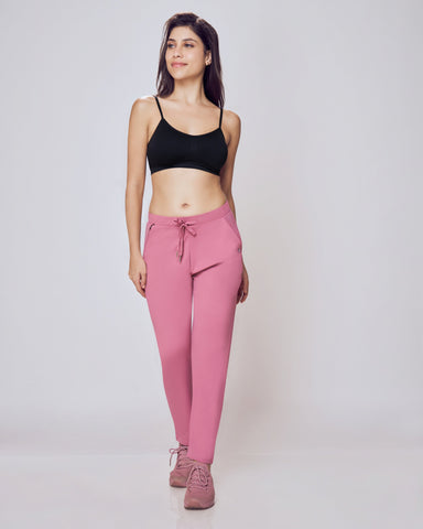 Woman wearing a black sports bra and pink leggings on a white background