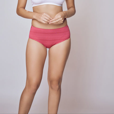 Woman wearing a white sports bra and red shorts on a gray background