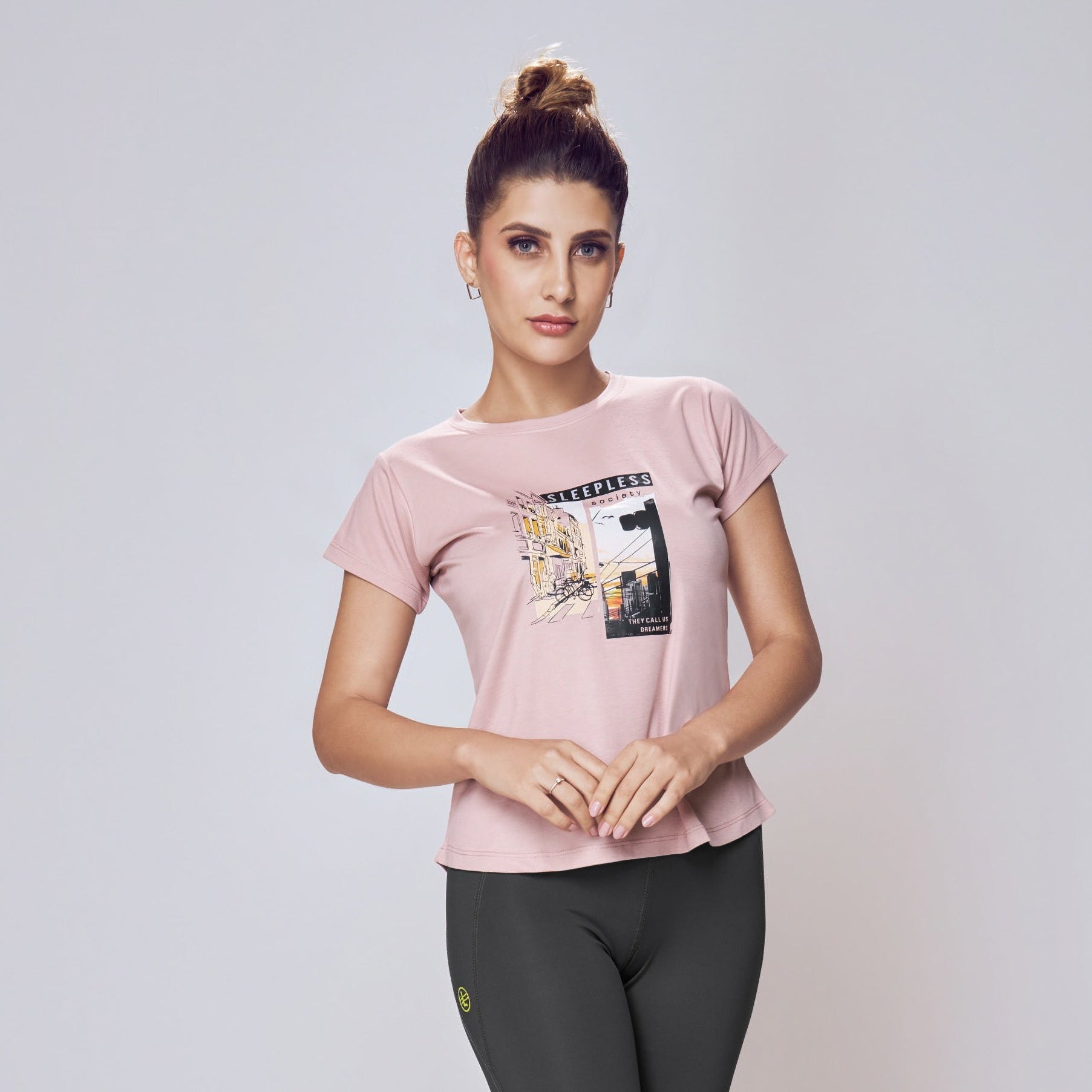 Woman wearing a pink t-shirt and black leggings on a white background