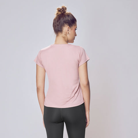 Woman wearing a pink t-shirt and black leggings on a plain background