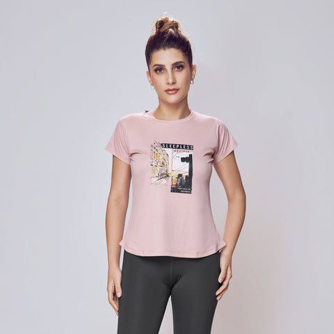 Woman wearing a pink t-shirt with a graphic design and black leggings on a white background