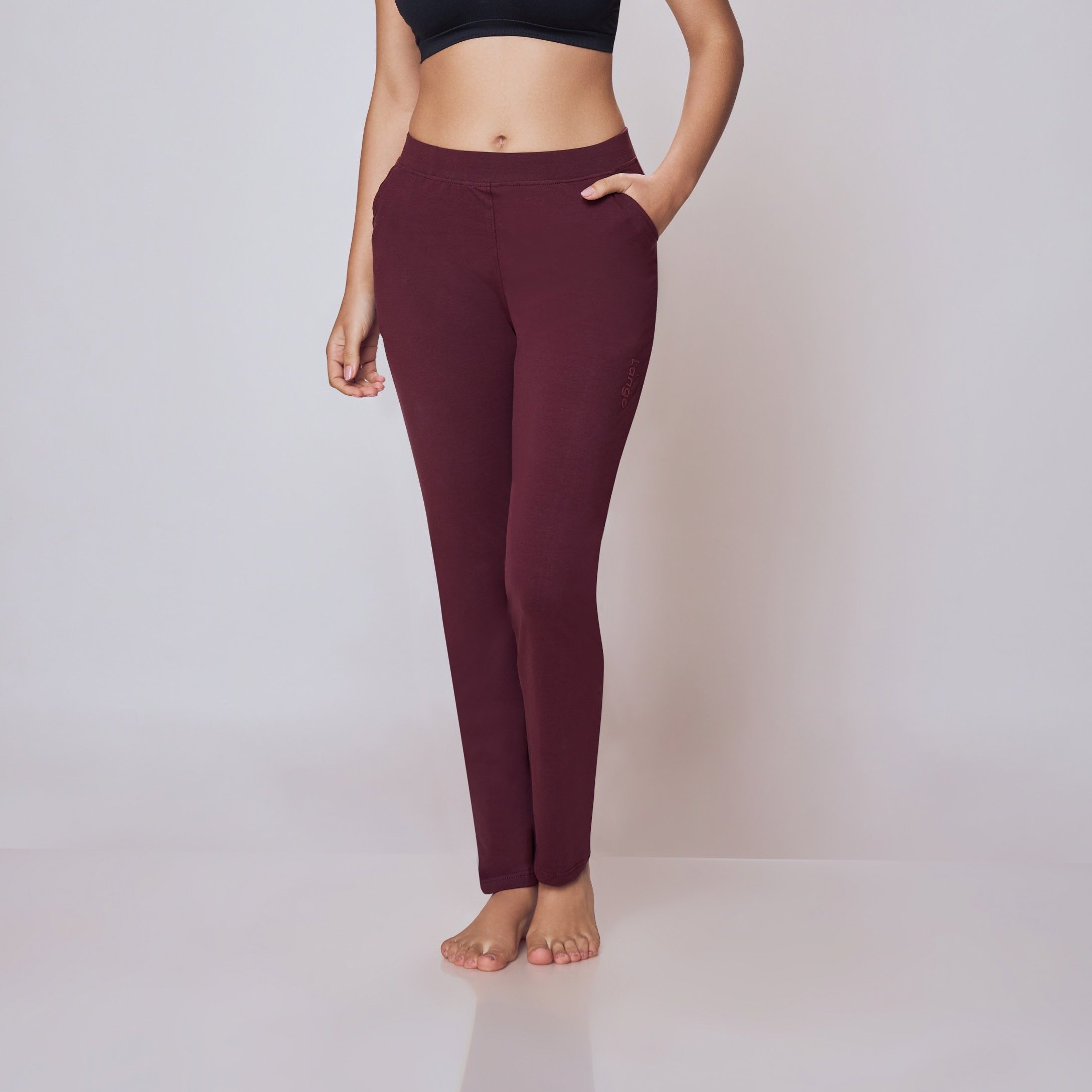 Woman wearing a black sports bra and maroon Power Move Track Pants on a white background