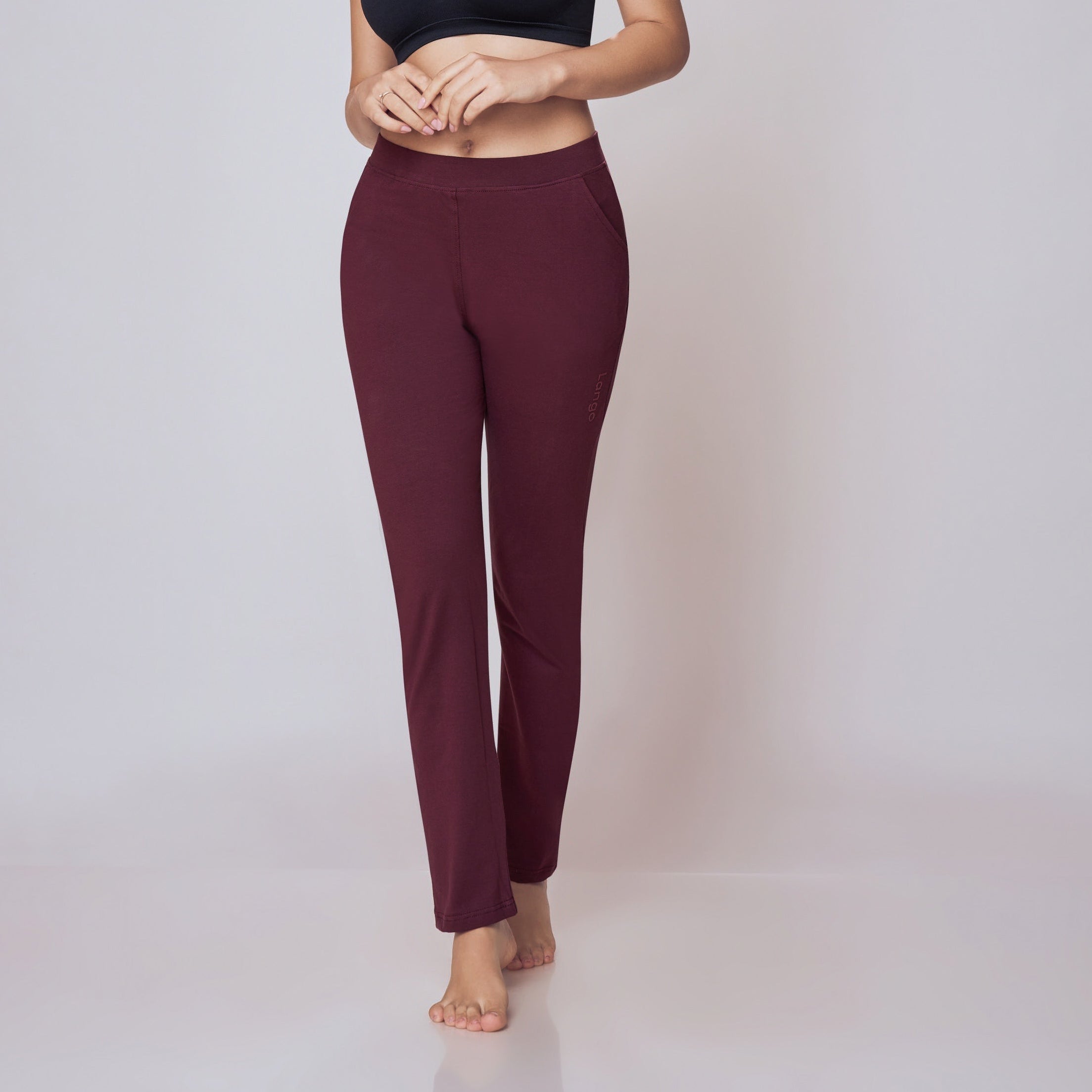 Woman wearing a black sports bra and maroon Power Move Track Pants on a light gray background