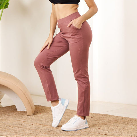 Woman in black sports bra and pink Power Move Track Pants posing in a minimalistic room.