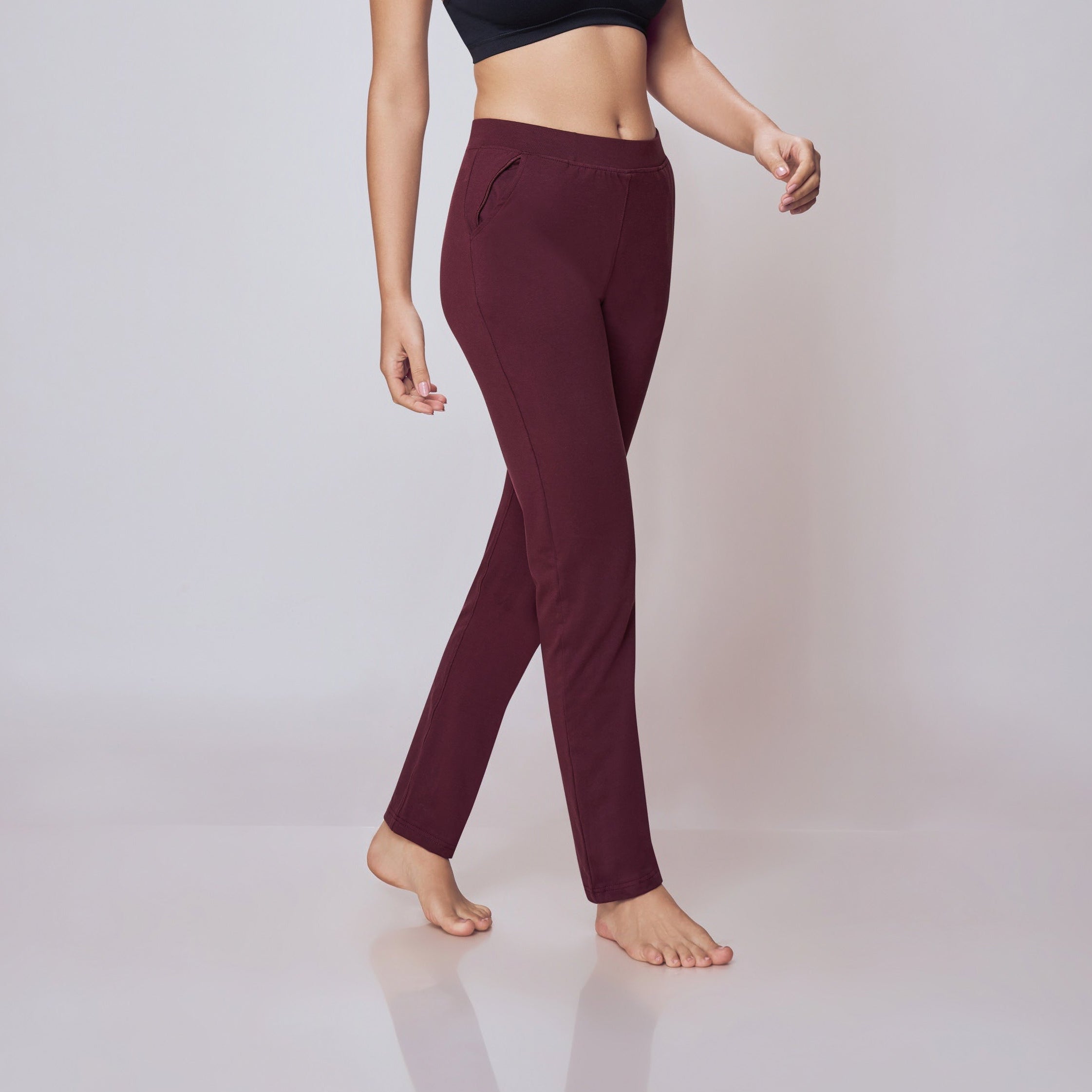 Woman wearing a black sports bra and maroon Power Move Track Pants on a white background
