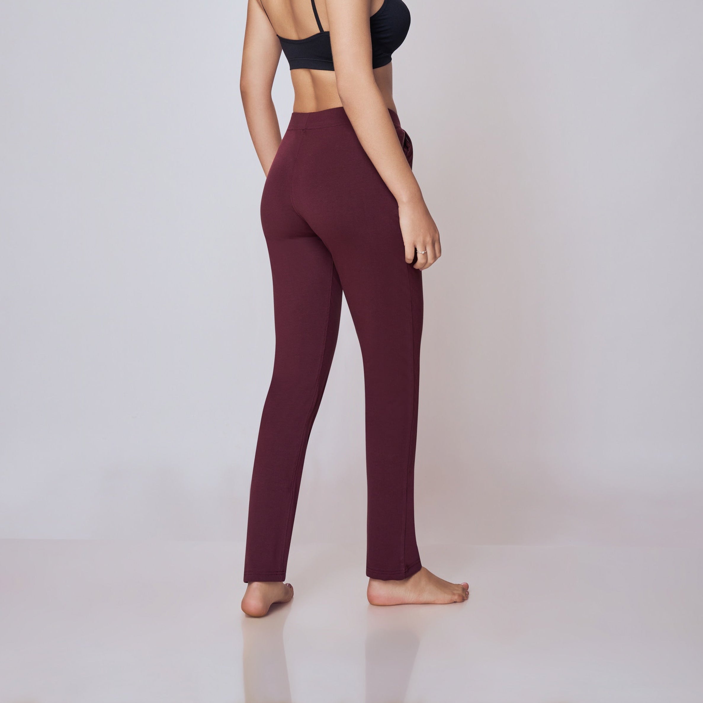 Woman wearing a black sports bra and maroon  Power Move Track Pants on a white background