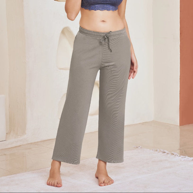 Woman wearing a blue sports bra and gray pants in a minimalistic room.