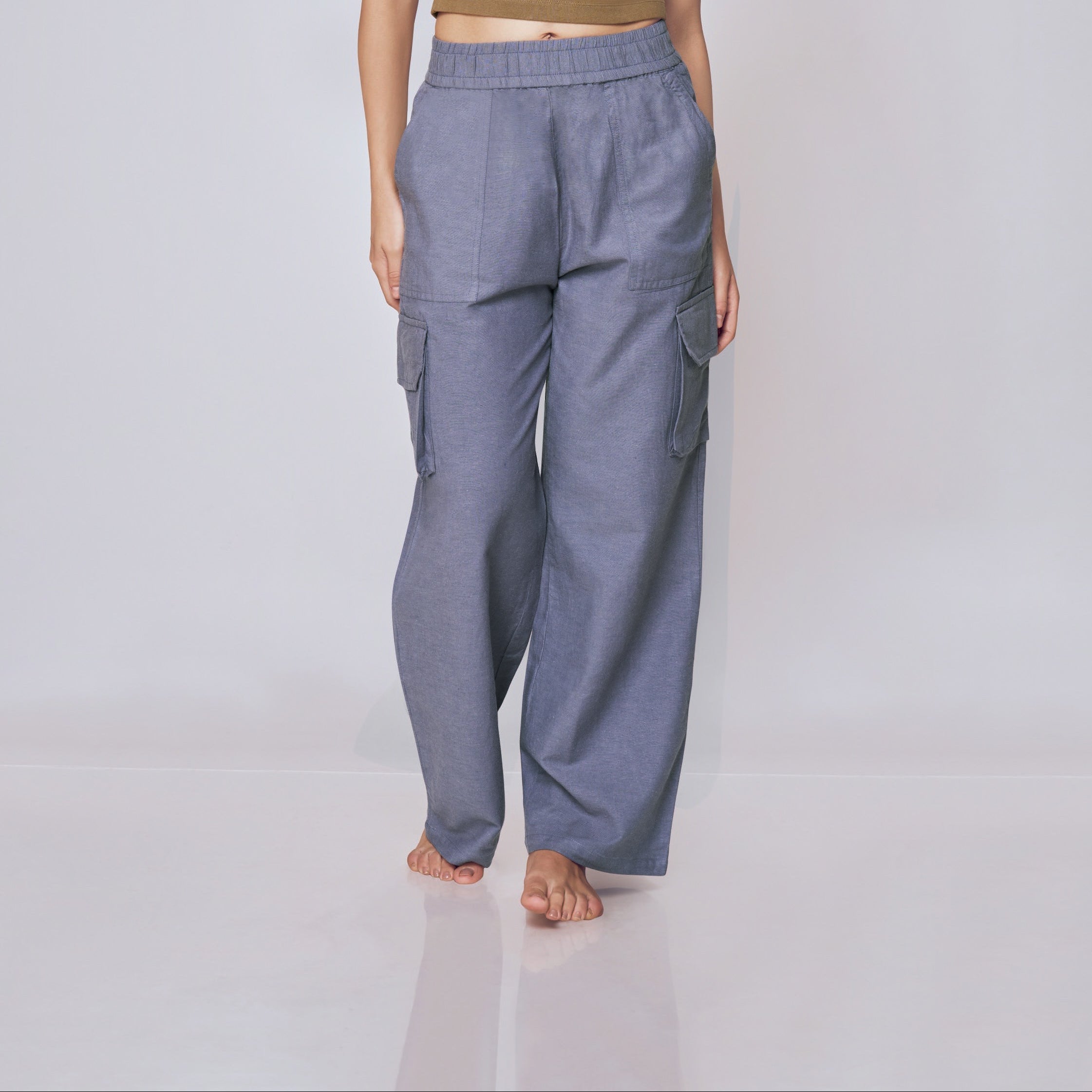 Woman wearing a green crop top and gray pants on a white background