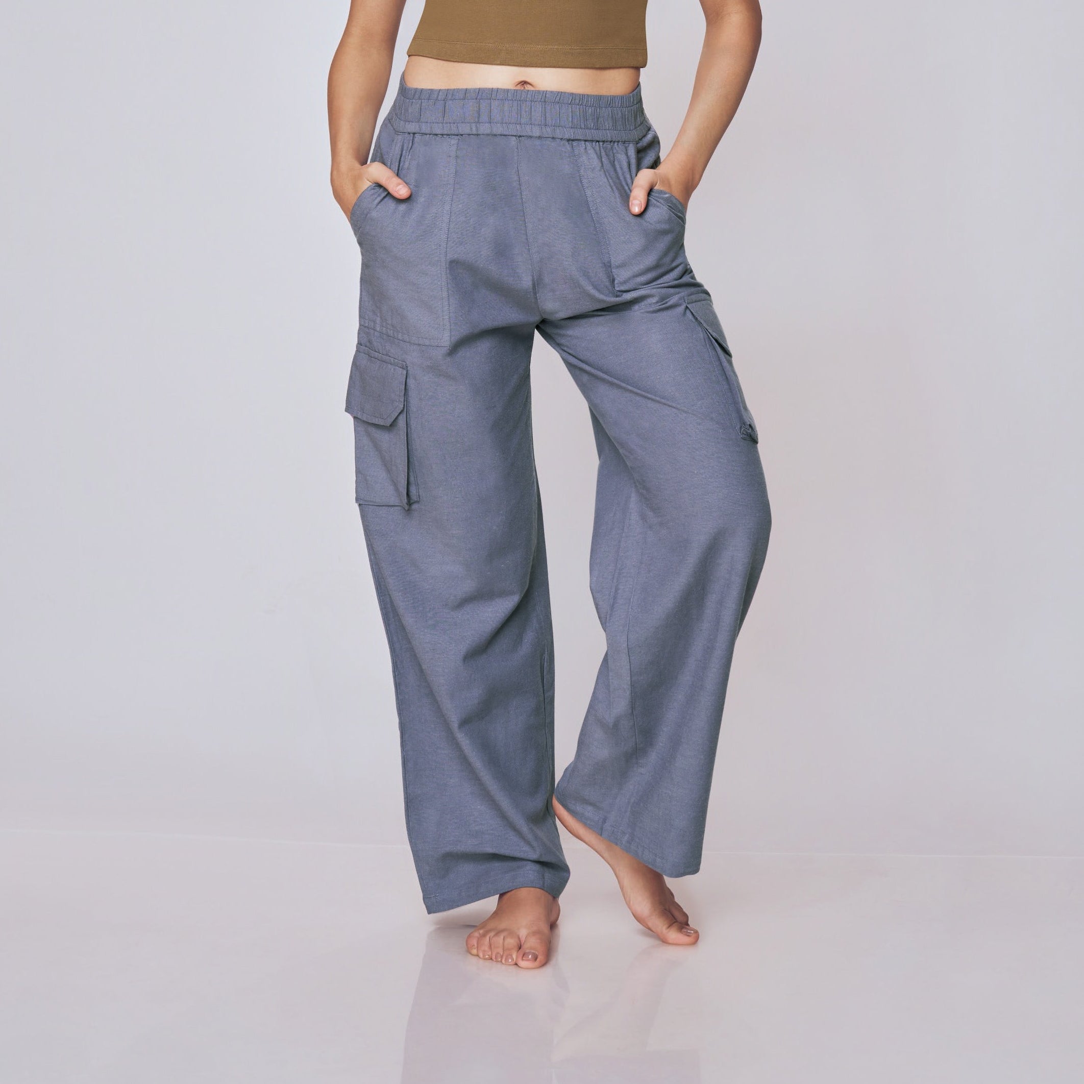 Woman wearing a brown top and gray cargo pants on a white background
