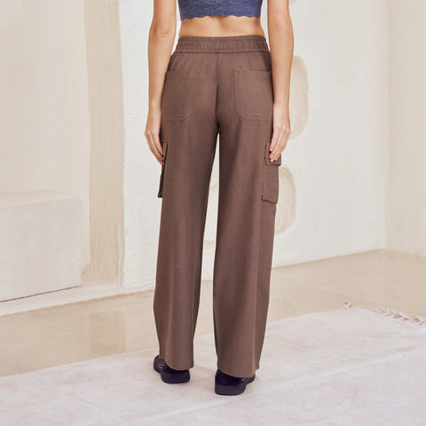 Woman wearing a blue top and brown pants in a modern, abstract room.