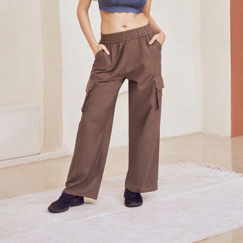 Woman in a blue top and brown cargo pants standing in a modern architectural setting.